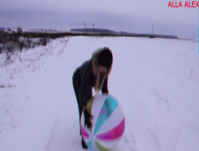 Alla plays with a beach ball on a snow-covered field.